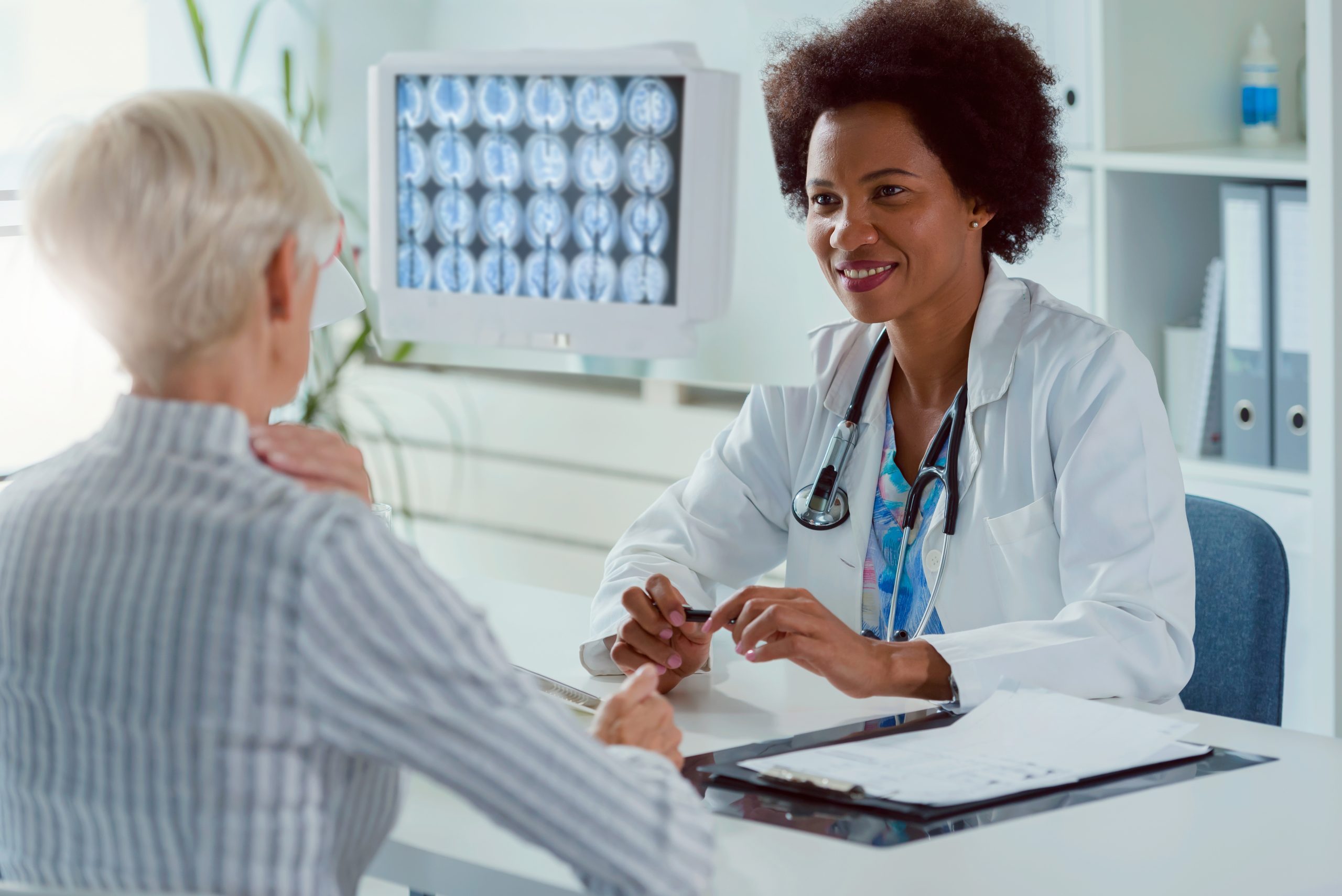 A female doctor sits at her office and examining elderly female patient; Shutterstock ID 1685724577; purchase_order: Limited 7/26/21