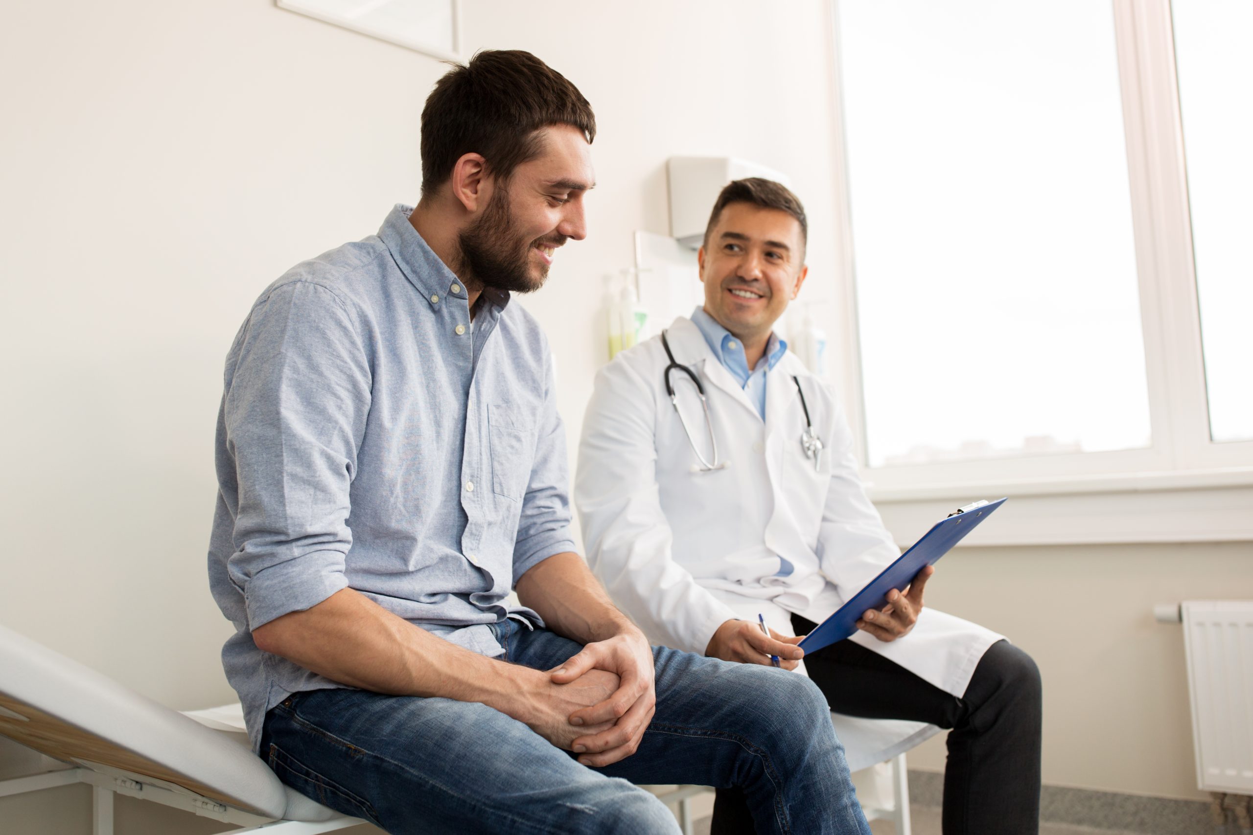 medicine, healthcare and people concept - smiling doctor with clipboard and young man patient meeting at hospital; Shutterstock ID 740979067; Purchase Order: comps; Job: ; Client/Licensee: ; Other: